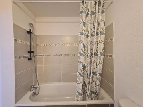 une baignoire avec un rideau de douche dans une salle de bain dans l'établissement Joli studio calme et balcon au cœur du Lubéron proche du centre et gare, à Cavaillon