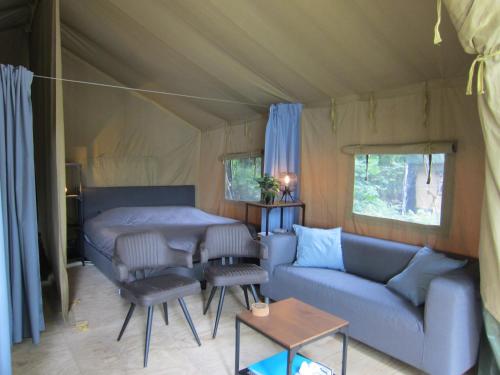 a living room with a couch and a table in a tent at Luxe safaritent op Landgoed de Leijen in Hensbroek