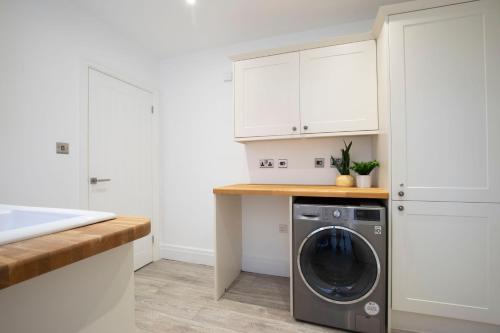 a washing machine in a kitchen with white cabinets at Lythwood House in Gloucester