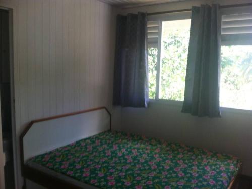 1 cama en un dormitorio con ventana en Teahupo'o house 5 min from wave, en Teahupoo