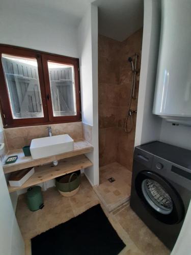 une salle de bain avec un lavabo et une machine à laver dans l'établissement Maison au pied de la st victoire avec piscine, à Pourrières