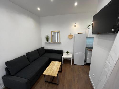 - un salon avec un canapé noir et un réfrigérateur dans l'établissement Montpellier Cœur Lumière, à Montpellier