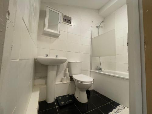 a white bathroom with a toilet and a sink at The Big 3 Bedroom London House 2 bathrooms in Woolwich