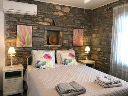 LigiaにあるSunset Villa with swimming pool at Tziaのベッドルーム1室(ランプ2つ、石壁付)