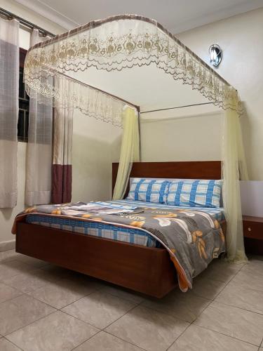 a bed with a canopy in a room at MiniPalais Bukoto in Kampala