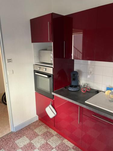 a small kitchen with red cabinets and a sink at Bel appartement 2 chambres n4 in Moulins