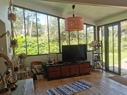 a living room with a flat screen tv and windows at la maison du bonheur in Seignosse
