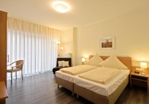Haller Hotel Garni في مونشاو: غرفة فندقية بسرير كبير وكرسي