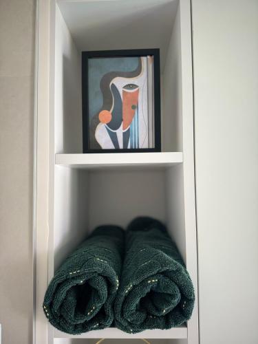 a towel shelf with a painting and towels at Sun Fun APT in Omiš