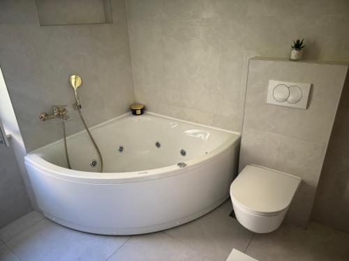 a white bathroom with a tub and a toilet at Sun Fun APT in Omiš