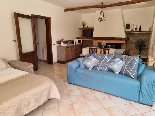 a living room with a blue couch and a kitchen at MAREMONTI Poggio Dei Pini Capoterra in Capoterra