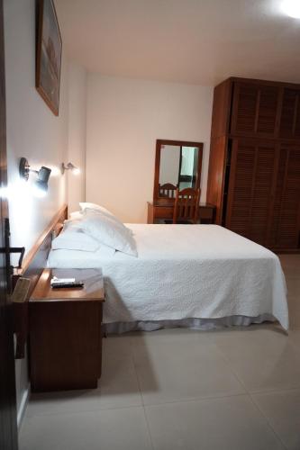 a bedroom with a bed and a table and a mirror at Pousada Brisa do Mar in Torres
