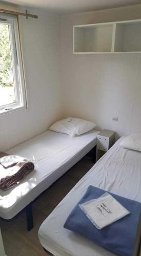 deux lits dans une petite pièce avec une fenêtre dans l'établissement Mobil home 4/6 personnes Camping les dunes - les Conches, à Longeville-sur-Mer