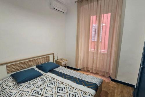 une chambre avec un lit avec des oreillers bleus et une fenêtre dans l'établissement Appartement rénové centre historique de Bastia à deux pas du Vieux Port, à Bastia