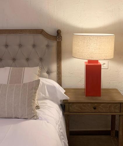 a red lamp on a table next to a bed at HOTEL RURAL SANTUI in Horcajuelo de la Sierra