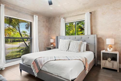 een slaapkamer met een groot bed en 2 ramen bij Entire Villa, North Miami Beach with pool on canal! in Miami