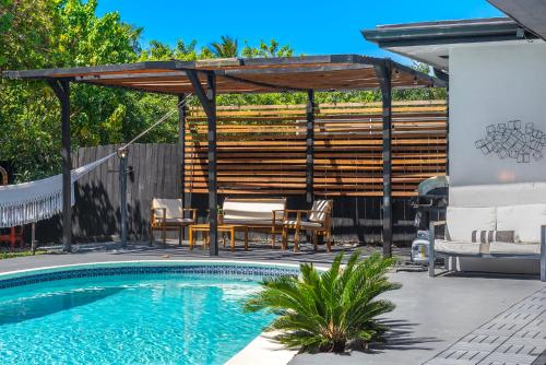 a patio with a swimming pool and a wooden pergola at Casa Olan - Luxury Family Oasis 3BR North Miami Beach Villa with Saltwater Pool & Canal Views in Miami