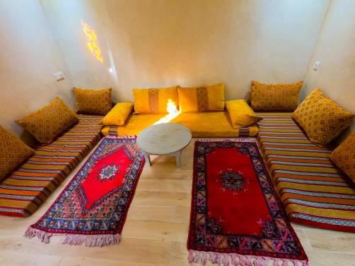 een woonkamer met een bank en een tafel met tapijten bij Cozy Tamraght 1 Bedroom apartement in Tamraght Ouzdar