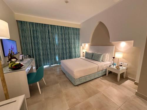 a hotel room with a bed and a desk with a computer at Sharm Club Beach Resort in Sharm El Sheikh