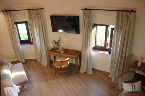 a room with a desk and a bed and a table and windows at HOTEL RURAL SANTUI in Horcajuelo de la Sierra