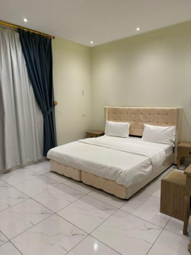 een slaapkamer met een groot bed met witte lakens bij أجنحة دارنـــــا للـــشقق الــمــفــروشــة in Abha