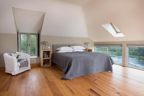 a bedroom with a bed and a chair and windows at Heiton Mill House in Kelso