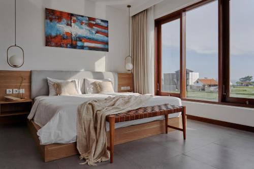 a bedroom with a large bed with a bench in it at Om Cemagi Beach Villa Canggu in Canggu