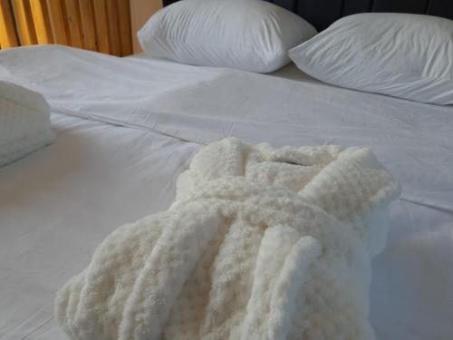 a white blanket on a white bed with pillows at Natura Bungalow in Ždrelo
