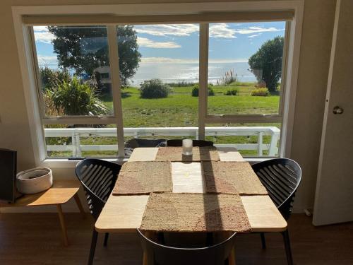 a table with chairs in front of a large window at Pohara's Beach House in Pohara