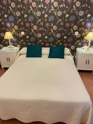 a bedroom with a white bed with a floral wallpaper at Apartamentos Turisticos La vida de antes in Consuegra