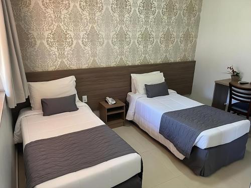 a hotel room with two beds and a table at Cataratas Park Hotel e Eventos in Foz do Iguaçu