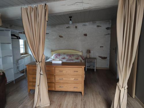 1 dormitorio con 1 cama, vestidor de madera y cortinas en Halte vendéenne atypique, en Saint-Germain-lʼAiguiller