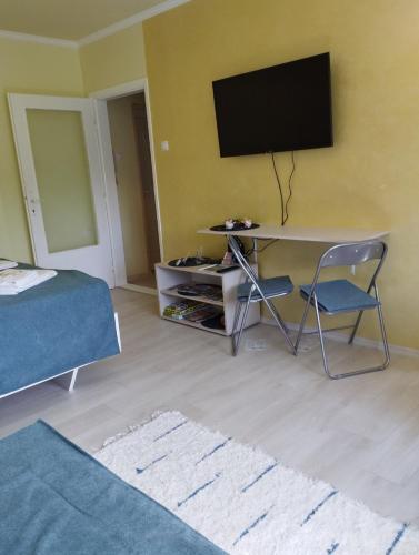 a bedroom with a desk with a television on a wall at Apartman Buba II in Palić