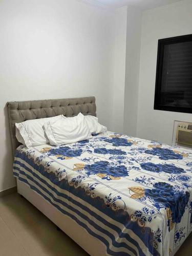 a bed with a blue and white blanket on it at Apartamento com vista do mar in Praia Grande