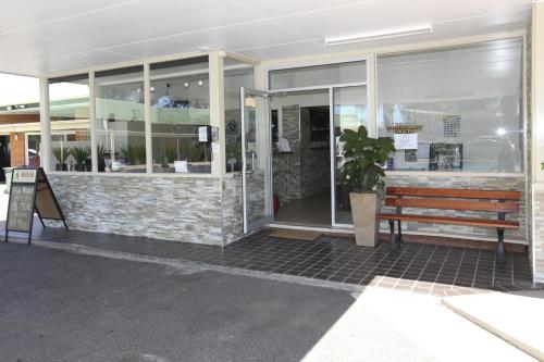 a building with a bench in front of a store at Matilda Motor Inn in Dubbo