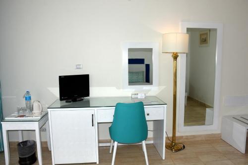 a desk with a computer and a blue chair at Sharm Club Beach Resort in Sharm El Sheikh