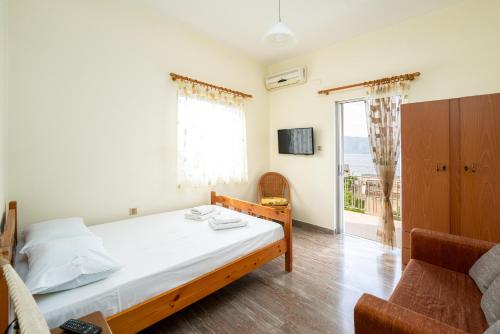 um quarto com uma cama, uma cadeira e uma janela em Sainis Rooms em Selianitika