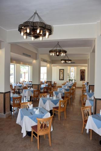 a dining room with blue tables and wooden chairs at Sharm Club Beach Resort in Sharm El Sheikh