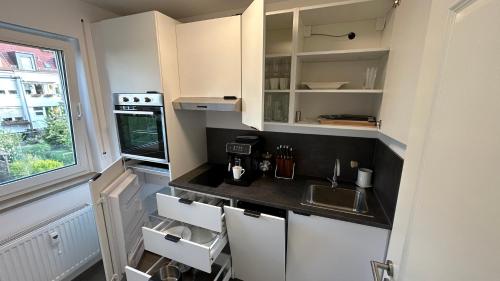 una pequeña cocina con armarios blancos y fregadero en Parkresidenz am Auensee Tolle Wohnung Neu - All Inclusive, en Leipzig