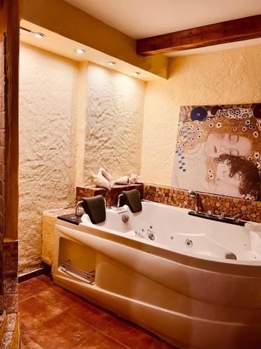 a bathroom with a tub with a painting on the wall at Landhaus de Gaspary in Seehausen am Staffelsee
