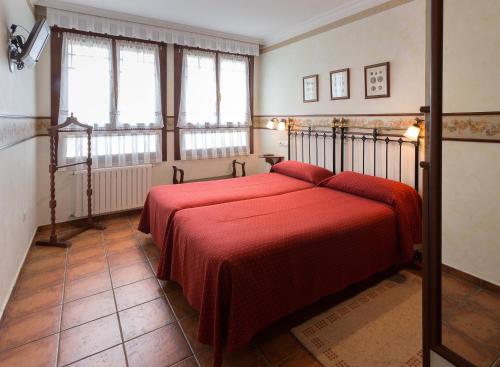 a bedroom with a bed with a red blanket at As Tapias Apartamentos in Tapia de Casariego
