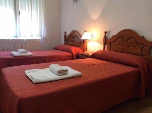 a hotel room with two beds with red sheets at Hospedería municipal la cultural in Saucelle
