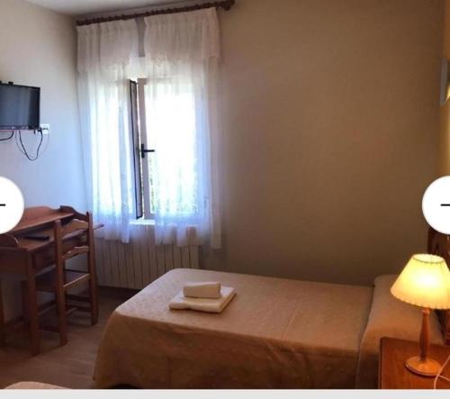um quarto com uma cama, uma secretária e uma janela em Hospedería municipal la cultural em Saucelle