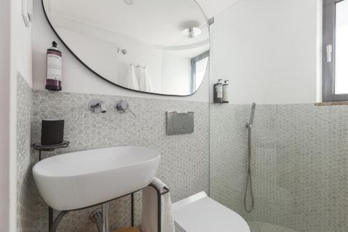 La salle de bains est pourvue d'un lavabo blanc et d'un miroir. dans l'établissement Urban Loft, à Porto