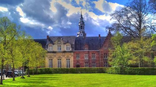 a large red brick building with a clock tower at De Wilden Ezel in Mol