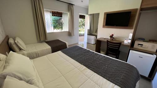a bedroom with a bed and a desk and a television at Cataratas Park Hotel e Eventos in Foz do Iguaçu