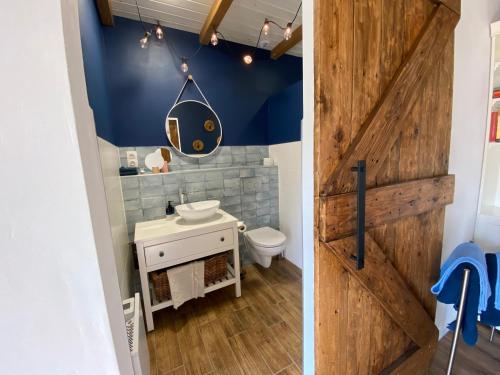 ein Badezimmer mit einer Holztür, einem Waschbecken und einem WC in der Unterkunft B&B by Mo in Etyek