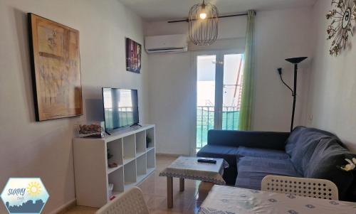 ein Wohnzimmer mit einem blauen Sofa und einem TV in der Unterkunft Sunny Churriana-Airport in Málaga