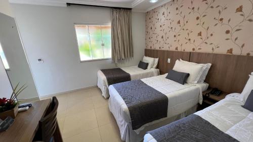 a hotel room with three beds and a desk at Cataratas Park Hotel e Eventos in Foz do Iguaçu