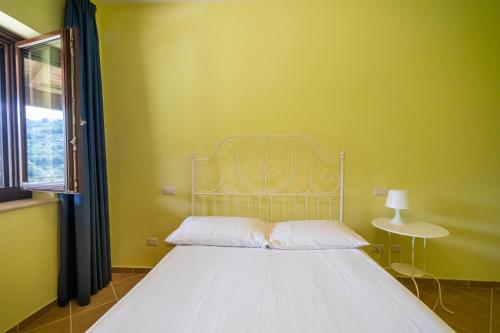 ein Schlafzimmer mit einem weißen Bett und einer gelben Wand in der Unterkunft Appartamento per quattro con piscina in villa in Agropoli